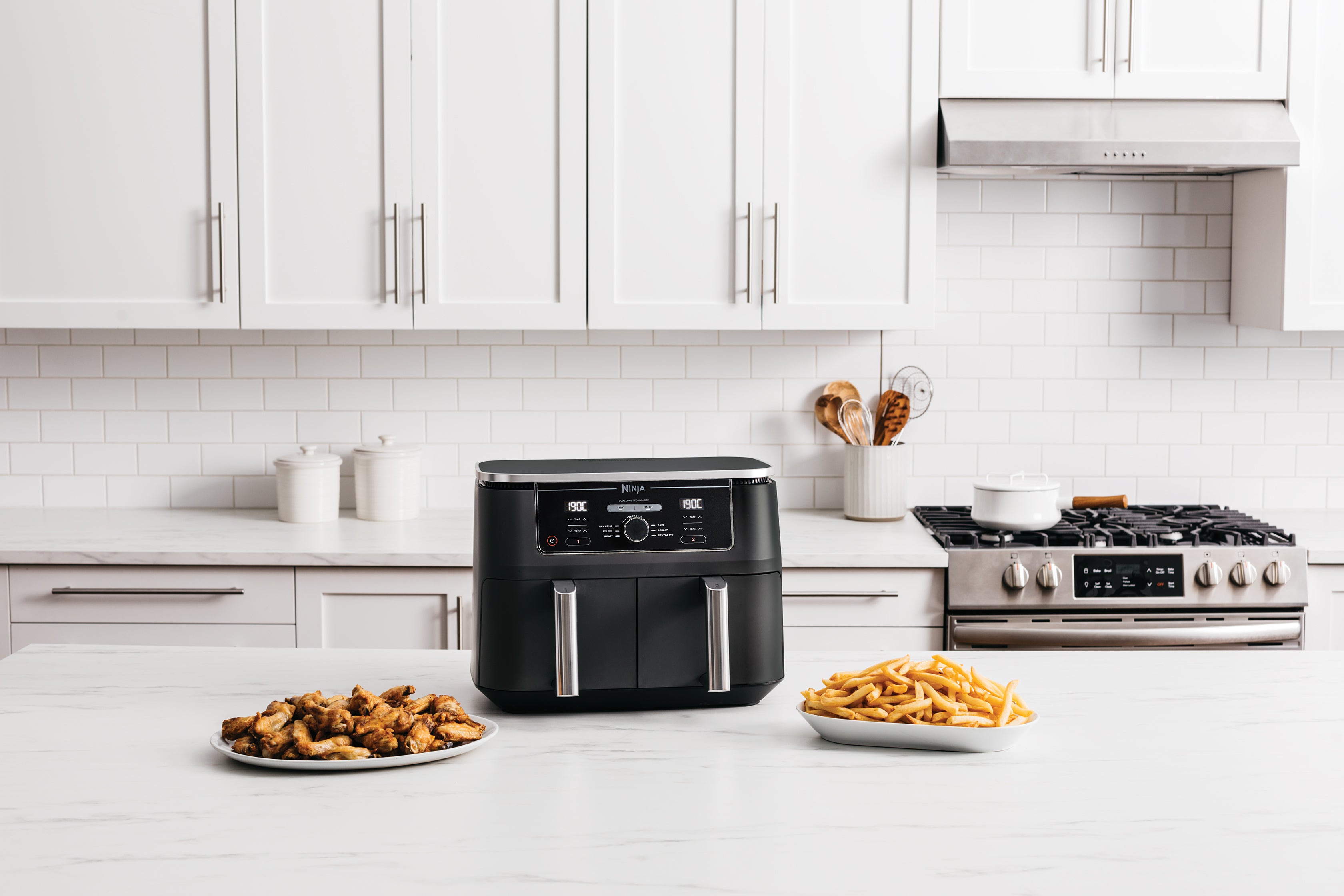 Ninja Dual Zone Airfryer mit goldbraunen Pommes und Wings auf Arbeitsplatte in heller Küche